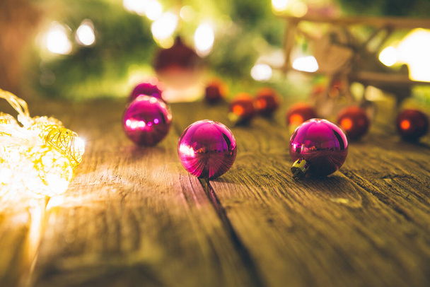 Christmas tree decorations laying on a rustic wooden table against christmas lights - Photo, image
