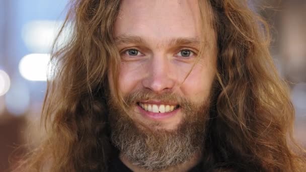 Portré kaukázusi férfi modell hipszter fickó hosszú vörös szőke haj és szakáll szürke haj mosolygott őszintén néz kamera pózol hitetlenül ráncoló szemöldök hunyorog a szemöldök gyanús - Felvétel, videó