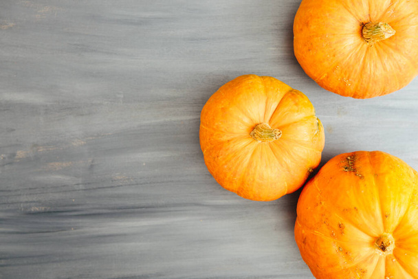 Top border of two orange pumpkins on a light gray wood background with copy space Thanksgiving and Halloween concept. View from above. Top view. Copy space for text and design - 写真・画像