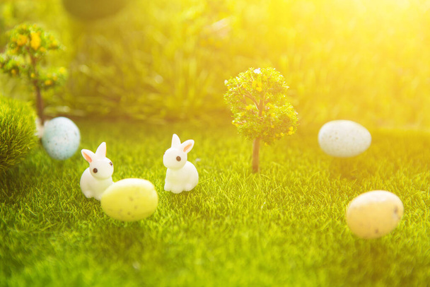 Rabbit toys with Easter eggs on spring green grass meadow. Happy Easter. - Fotó, kép
