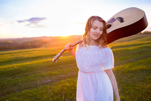 portrait of the beautiful young woman  with guitar in the field - Fotoğraf, Görsel