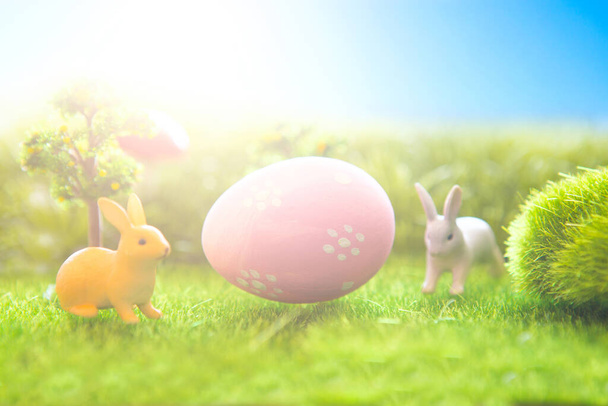 Rabbit toys with easter eggs on a meadow grass. - 写真・画像