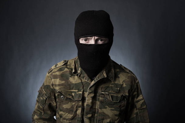 Terrorist in military uniform and mask on dark background - Photo, image
