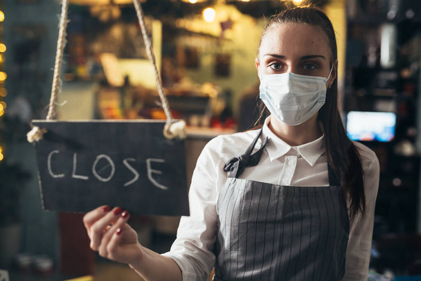 waitress closing cafe or restaurant due coronavirus, holding close sign - Foto, afbeelding
