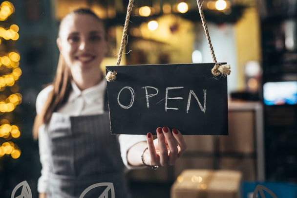 waitress opening cafe or restaurant, holding open sign - Valokuva, kuva