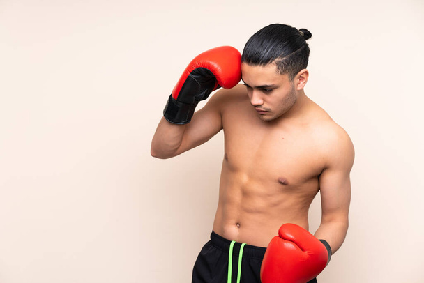 Asyalı sporcu boks eldivenleriyle bej arka planda izole edilmiş. - Fotoğraf, Görsel