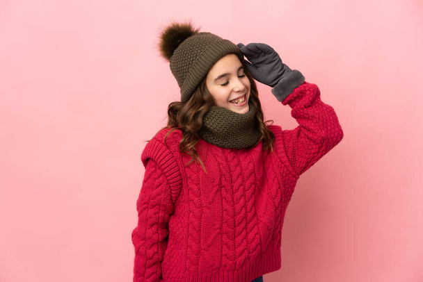 Κοριτσάκι με χειμερινό καπέλο απομονωμένο σε ροζ φόντο χαμογελώντας πολύ - Φωτογραφία, εικόνα