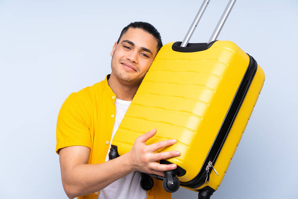 Asian handsome man isolated on blue background in vacation with travel suitcase - Fotografie, Obrázek