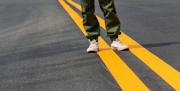 Чоловіки в кросівках, що ходять по вулицях з жовтими лініями
. - Фото, зображення