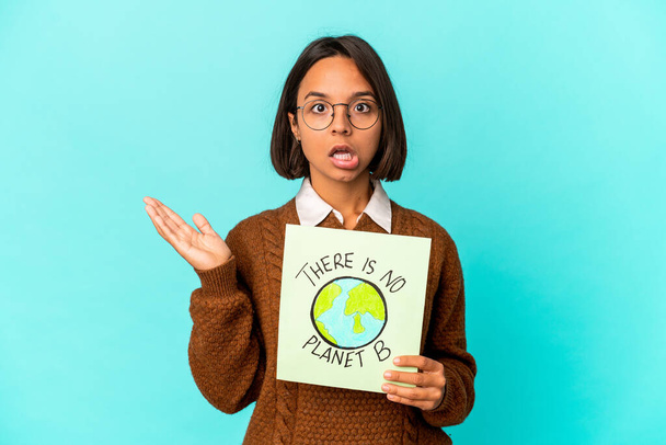 Young hispanic mixed race woman holding a planet save placard surprised and shocked. - Photo, Image