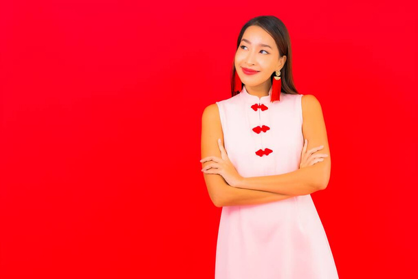 Portrait beautiful young asian woman wear chinese new year clothing on red background - Foto, imagen