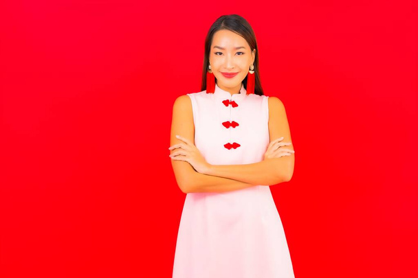 Portrait beautiful young asian woman wear chinese new year clothing on red background - Фото, зображення