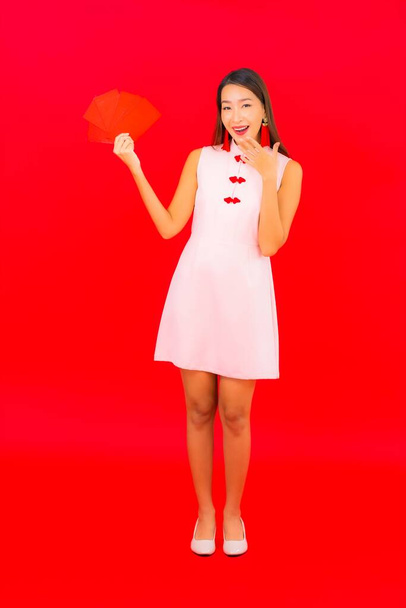 Retrato hermosa joven mujer asiática con sobre rojo letra sobre fondo rojo - Foto, imagen