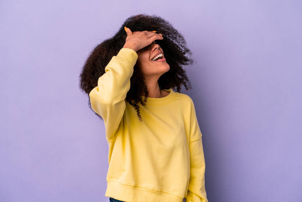 Mladá africká americká kudrnatá žena izolovaná na purpurovém pozadí se radostně směje a drží ruce za hlavu. Koncept štěstí. - Fotografie, Obrázek