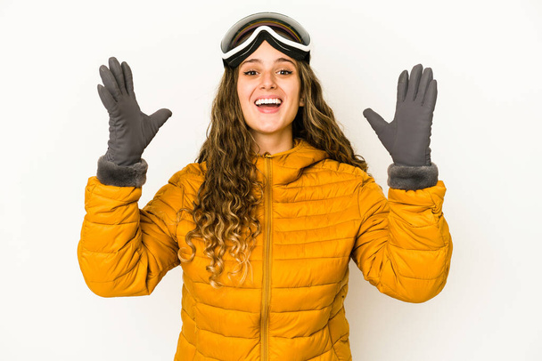 Jeune femme caucasienne snowboarder isolé recevant une agréable surprise, excité et levant les mains. - Photo, image