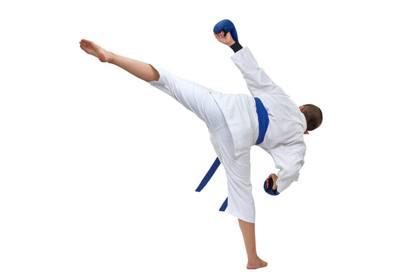 Σε karategi αγόρι αθλητής εκτελεί μια κλωτσιά σε λευκό απομονωμένο φόντο - Φωτογραφία, εικόνα