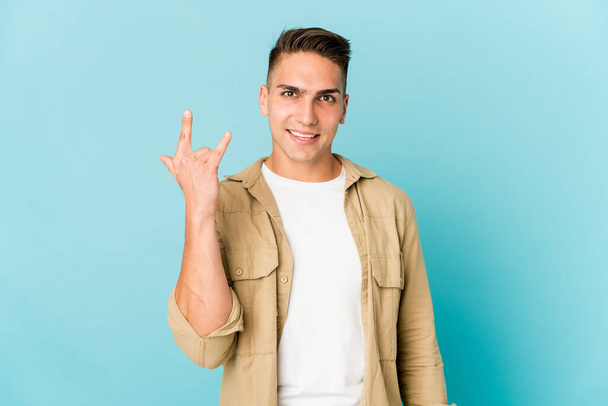 Young caucasian handsome man isolated showing a horns gesture as a revolution concept. - Foto, Imagen