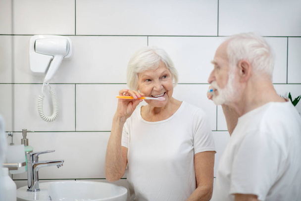 Elderly couple brushing their teeth together and feeling good - Foto, afbeelding