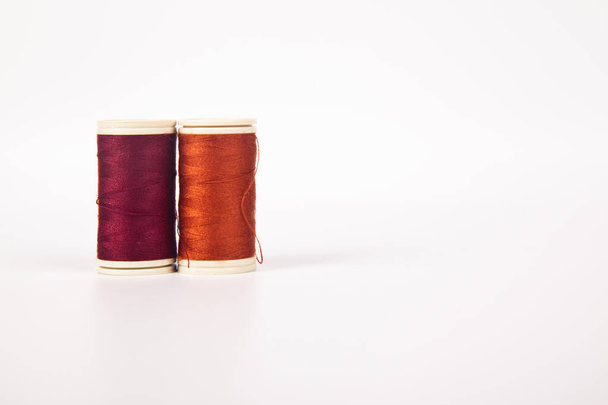 Spools and bobbins of thread for sewing in different red orange, isolated on white background - Photo, Image