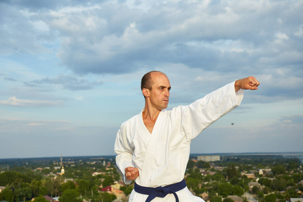 Muodollinen harjoitukset karate urheilija suorittaa taustalla kaupungin - Valokuva, kuva