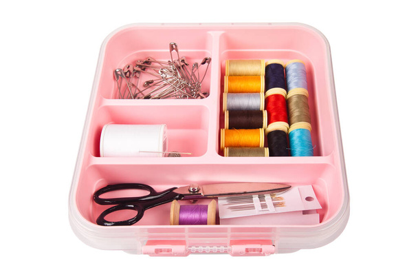 Vaaleanpunaisessa muovisessa ompelulaatikossa on kierteet sakset ja neulat. Eristetty valkoisella pohjalla - Valokuva, kuva