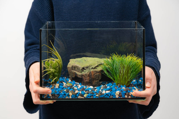 Person mit Aquarium ohne Wasser und Fisch auf weißem Hintergrund. Faustpfand. - Foto, Bild