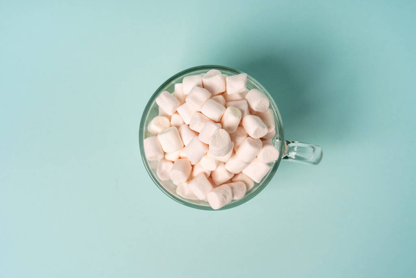 Λευκό ζαχαρωτό σε γυάλινη κούπα σε μπλε φόντο. Παγκόσμια ημέρα διαβήτη έννοια. - Φωτογραφία, εικόνα