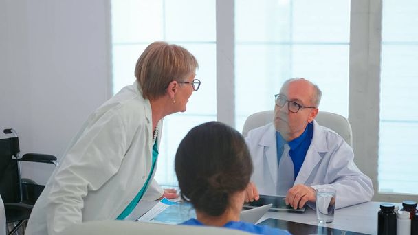 Ώριμη γυναίκα γιατρός μιλάμε για τη διάγνωση του ασθενούς κατά τη διάρκεια της συνάντησης - Φωτογραφία, εικόνα