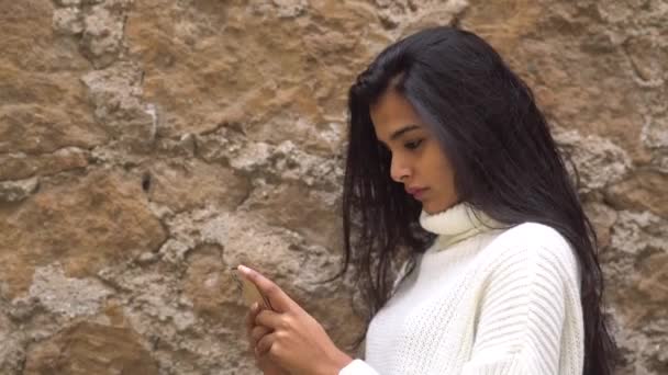 Tijd verspillen online. Een jong tienermeisje dat neerkijkt op haar smartphone. Selectieve focus - Video