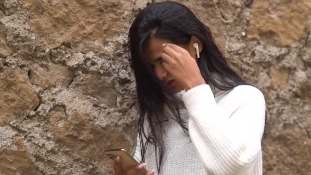 Marnowanie czasu online. Młoda nastolatka spogląda w dół na smartfona. Skupienie selektywne - Materiał filmowy, wideo