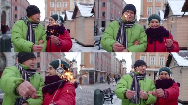 Multi-screen shot senior coppia che tiene scintille luci bengala godendo di Natale sulla strada della città - Filmati, video