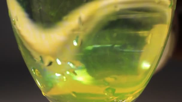 Стеклянное шампанское с водой и жидким цветом, разливающимся по поверхности  - Кадры, видео