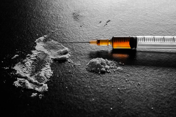 Şırıngada eroin ve siyah tahta üzerinde toz eroin. Bağımlılık yapıcı madde, uyuşturucu, alışkanlık yapıcı madde kavramı. - Fotoğraf, Görsel