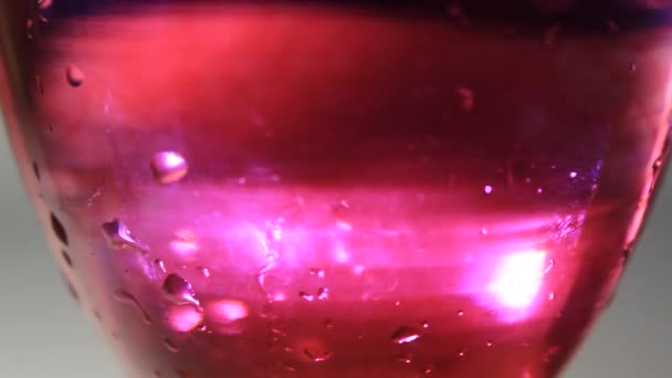 Champanhe de vidro com água e fluxo de cor líquida  - Filmagem, Vídeo