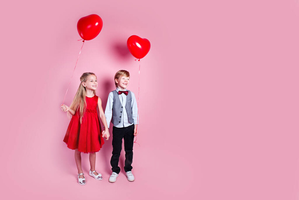 Valentines day. Two happy children with heart shape air balloons on pink studio background - Φωτογραφία, εικόνα