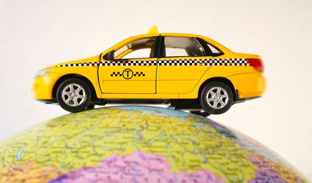  yellow taxi car - metal toy model - on globe  isolated on white  background. empty copy space for inscription.   - Fotoğraf, Görsel