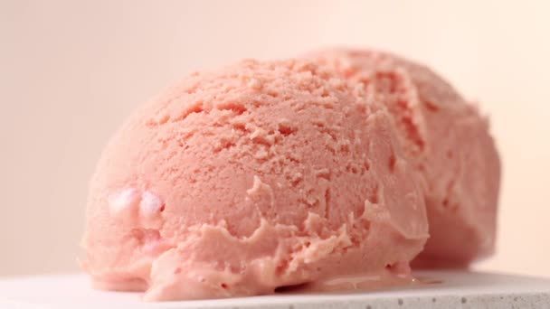 gros plan de deux boules de crème glacée rose et sauce au chocolat coulant tournant sur fond beige - Séquence, vidéo