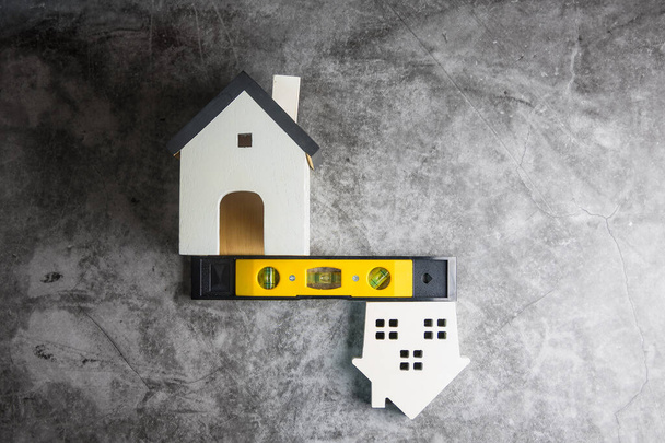 Holz weißes Haus Spielzeug und Bauwerkzeuge auf grau-schwarzem Zementboden Hintergrund mit Kopierraum. Immobilienkonzept, Neues Haus.Home Reparaturkonzept - Foto, Bild