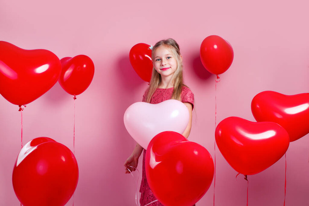 Valentines day. Little cute girl with red heart balloons on pink studio background - Foto, Imagem