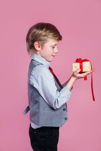 Valentines day. Little boy with gift box on pink studio background - Photo, Image