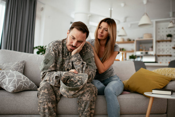 Przygnębiony żołnierz siedzący na kanapie z żoną. Młody marynarz z PTSD. - Zdjęcie, obraz