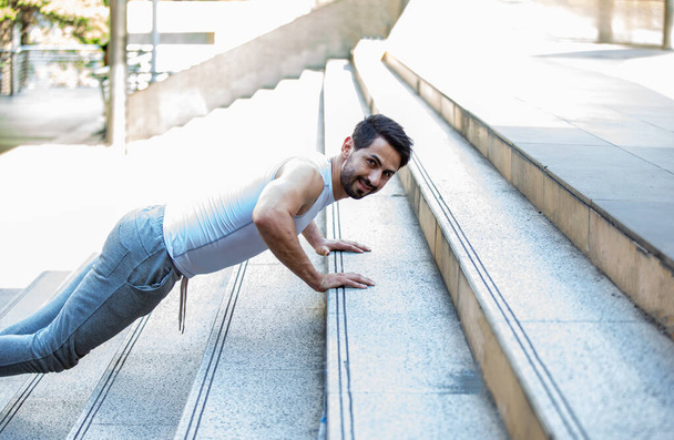 joven guapo haciendo ejercicios de flexiones en las escaleras de la ciudad - Foto, Imagen