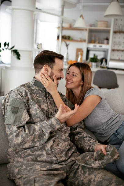 Onnellinen sotilas yllättää vaimonsa kotona. Nuori sotilas halaus vaimo. - Valokuva, kuva