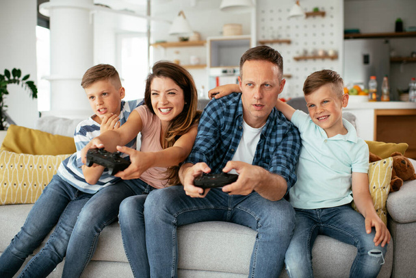  Happy loving couple are playing video games with kids at home. - Valokuva, kuva