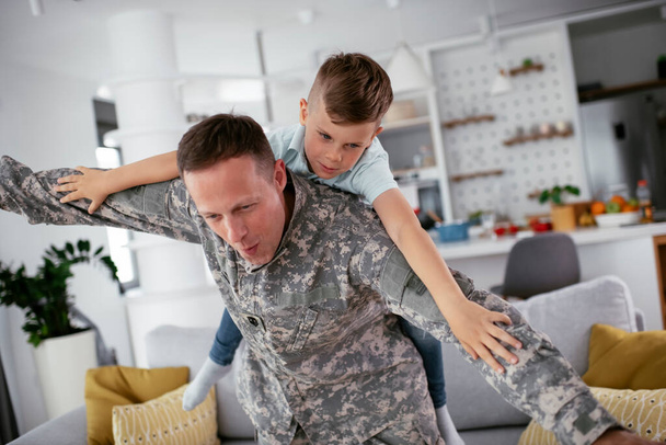 wojskowy człowiek bawi się z synem w domu  - Zdjęcie, obraz