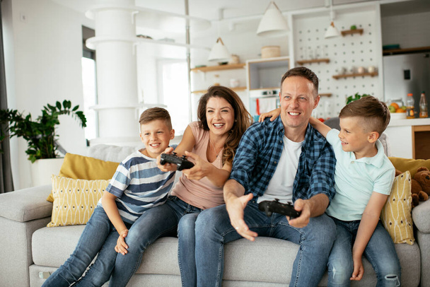  Feliz pareja amorosa están jugando videojuegos con los niños en casa. - Foto, imagen