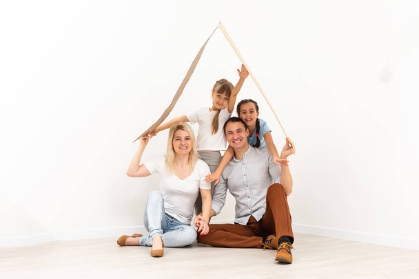 Happy family sitting on wooden floor. Father, mother and child having fun together. Moving house day, new home concept - Фото, зображення