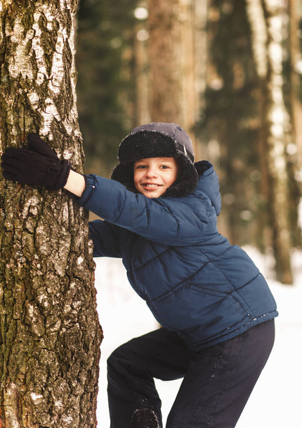 Poika kiipeää puuhun talvella metsässä - Valokuva, kuva