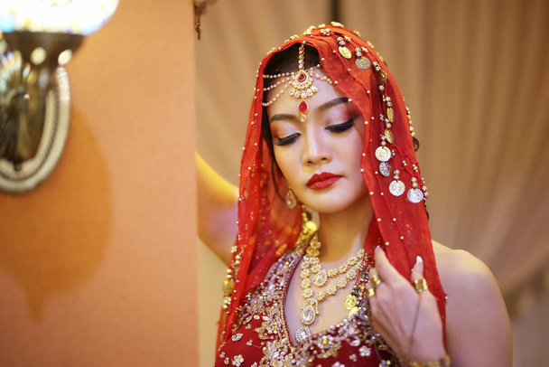 портрет красивой индийской девушки в костюме сари. Молодая индуистка модель с золотым набором ювелирных украшений кундан. Традиционный индийский костюм lehenga choli . - Фото, изображение