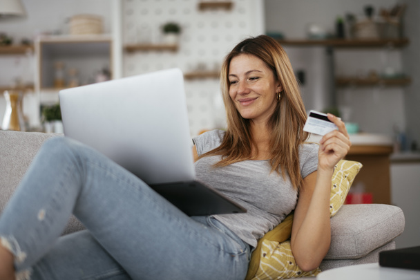 Junge Frau mit Kreditkarte und Laptop zu Hause. Schöne Frau kaufen online. - Foto, Bild